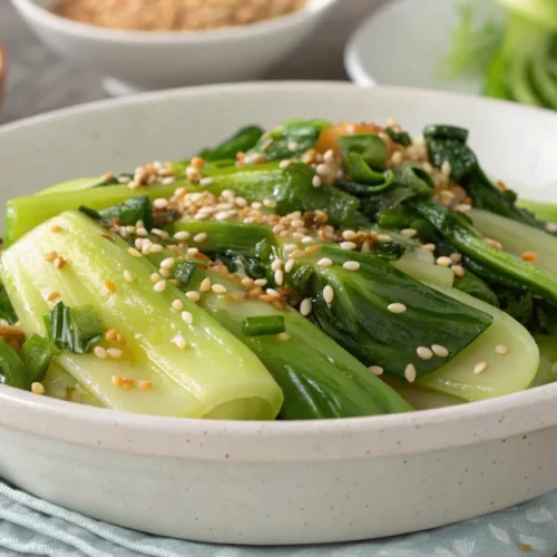 Beautiful landscape shot of stir-fried Pak Choi in a white ceramic bowl, garnished with sesame seeds and green onions, steami