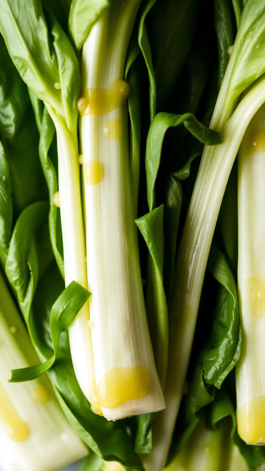 Close-up overhead shot of tender green pak choi with white stems glistening with sesame oil, soft natural light, fresh herb g